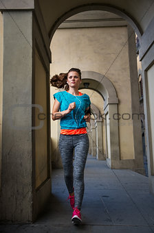 Fitness female with earphones is jogging outdoors