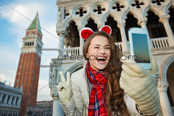 Woman taking Christmas selfie and showing victory in Venice