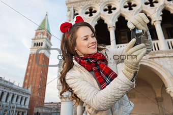 Happy woman tourist taking photos of sights in Christmas Venice