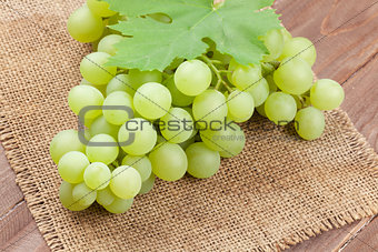 Bunch of white grapes with leaves over burlap