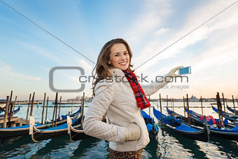 Woman traveler taking photos on embankment in Venice, Italy
