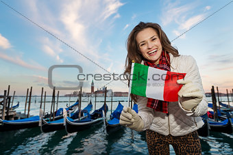 Woman traveler showing Italian flag on embankment in Venice