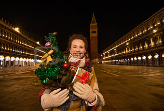 Woman with Christmas tree and gift standing on Piazza San Marco