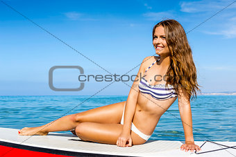 Woman sitting over a paddle surfboard