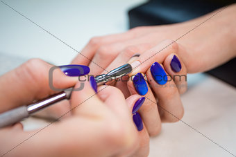 Manicurist removing cuticle from the girl nail