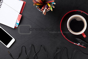 Desk with notepad, coffee, smartphone and headphones