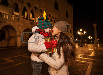 Happy mother hugging child with Christmas gift box in Venice