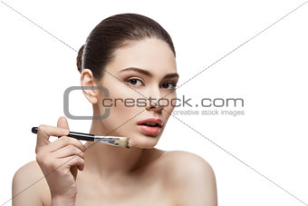Beautiful girl applying foundation with brush