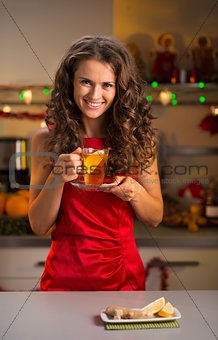 Woman having cup of ginger tea in christmas decorated kitchen