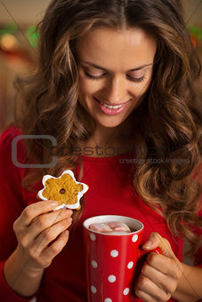 Woman having cup of chocolate and cookie in Christmas kitchen