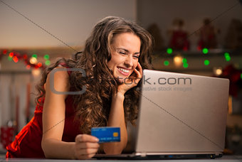 Woman with credit card choosing Christmas gifts on laptop