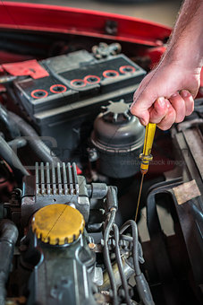 Car mechanic in auto repair service checking oil
