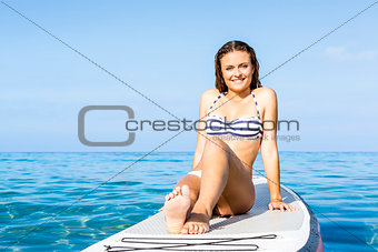 Woman sitting over a paddle surfboard