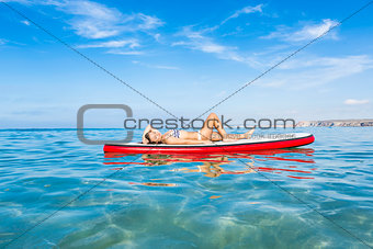 Woman relaxing over a paddle surfboard