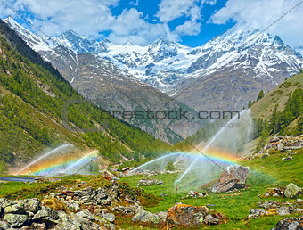 Rainbows in irrigation water spouts in Summer Alps mountain 