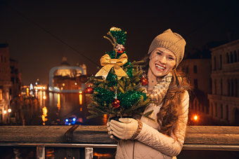 Young woman with Christmas tree standing on a bridge in Venice