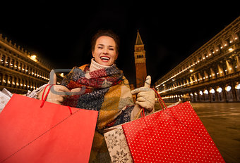 Woman with shopping bags showing thumbs up on Piazza San Marco