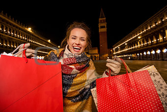 Excited woman in winter coat showing shopping bags in Venice