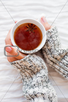 Women holds a cup of hot tea with anise star. Cozy morning at ho
