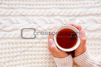 Women holds a cup of hot tea with anise star. Beautiful fabric b