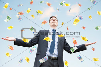 Happy businessman standing in the rain of  money