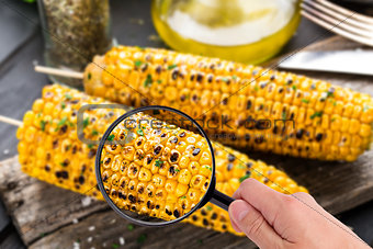 Magnifying glass examining grilled corn cob