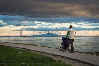 Mother with Baby Stroller Walking by the Sea