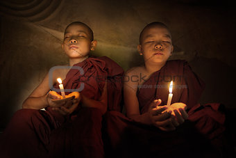 Buddhist novices praying with candlelight