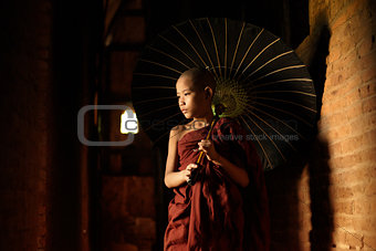 Buddhist novice walking with umbrella