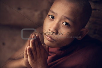 Buddhist novice monk praying in monastery