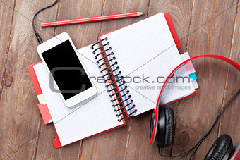 Desk with notepad, smartphone and headphones