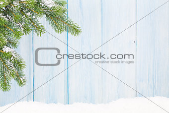 Christmas fir tree in snow in front of wooden wall
