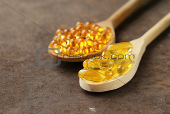 food supplement of fish oil capsules in a wooden spoon - healthy food