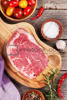 Raw beef steak and spices on wooden table