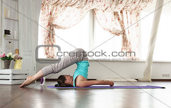 young beautiful girl practicing yoga at home.