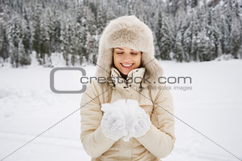Woman looking on snow in hands while standing outdoors