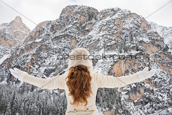 Seen from behind young woman rejoicing in winter outdoors