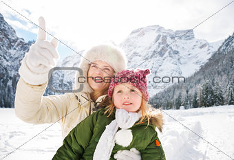 Mother pointing up on something to child in winter outdoors