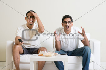 Men watching football match on tv at home