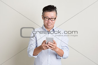 Mature Asian man using smartphone