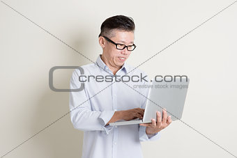 Mature Asian man using laptop pc