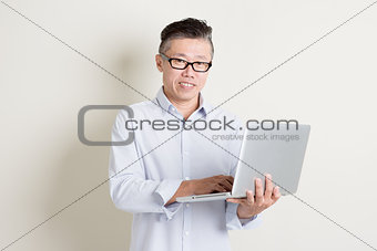 Mature Asian man using laptop computer