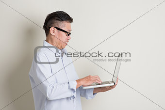 Mature Asian man using computer notebook