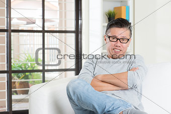 Mature 50s Asian male sitting at home.