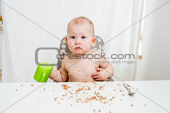 Little baby eating at kitchen. Happy messy eater
