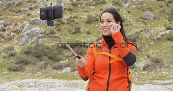 Smiling young backpacker using a selfie stick