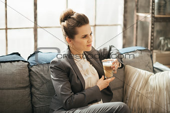 Young businesswoman is sitting on couch with cup of coffee