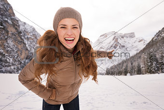 Happy young woman outdoors pointing on snow-capped mountains