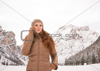 Woman talking mobile phone outdoors among snow-capped mountains
