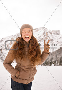 Woman showing victory outdoors among snow-capped mountains